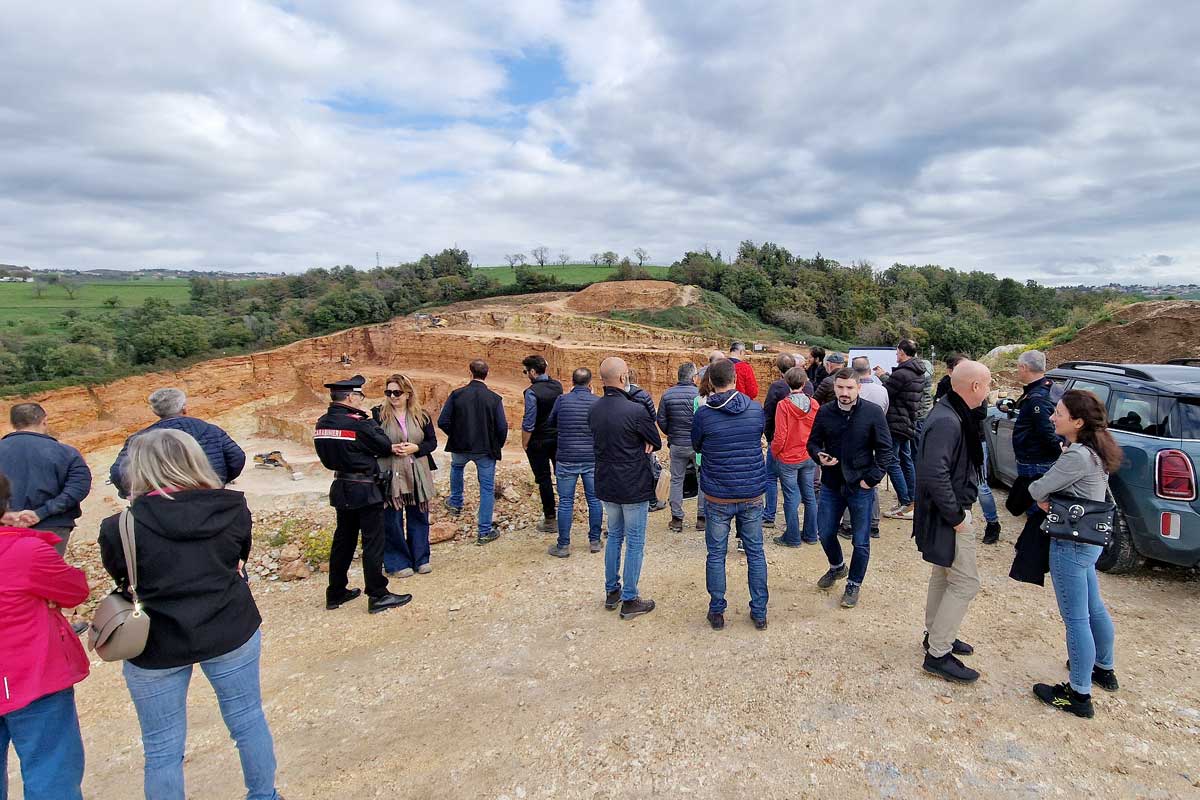 Gruppo di persone di schiena in visita ad un sito estrattivo a cielo aperto